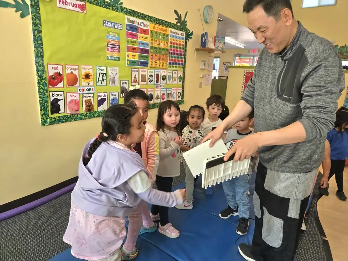 Child doing a Tae Kwon Do activity with the lecturer breaking a board at Newport Ave Preschool enrichment program