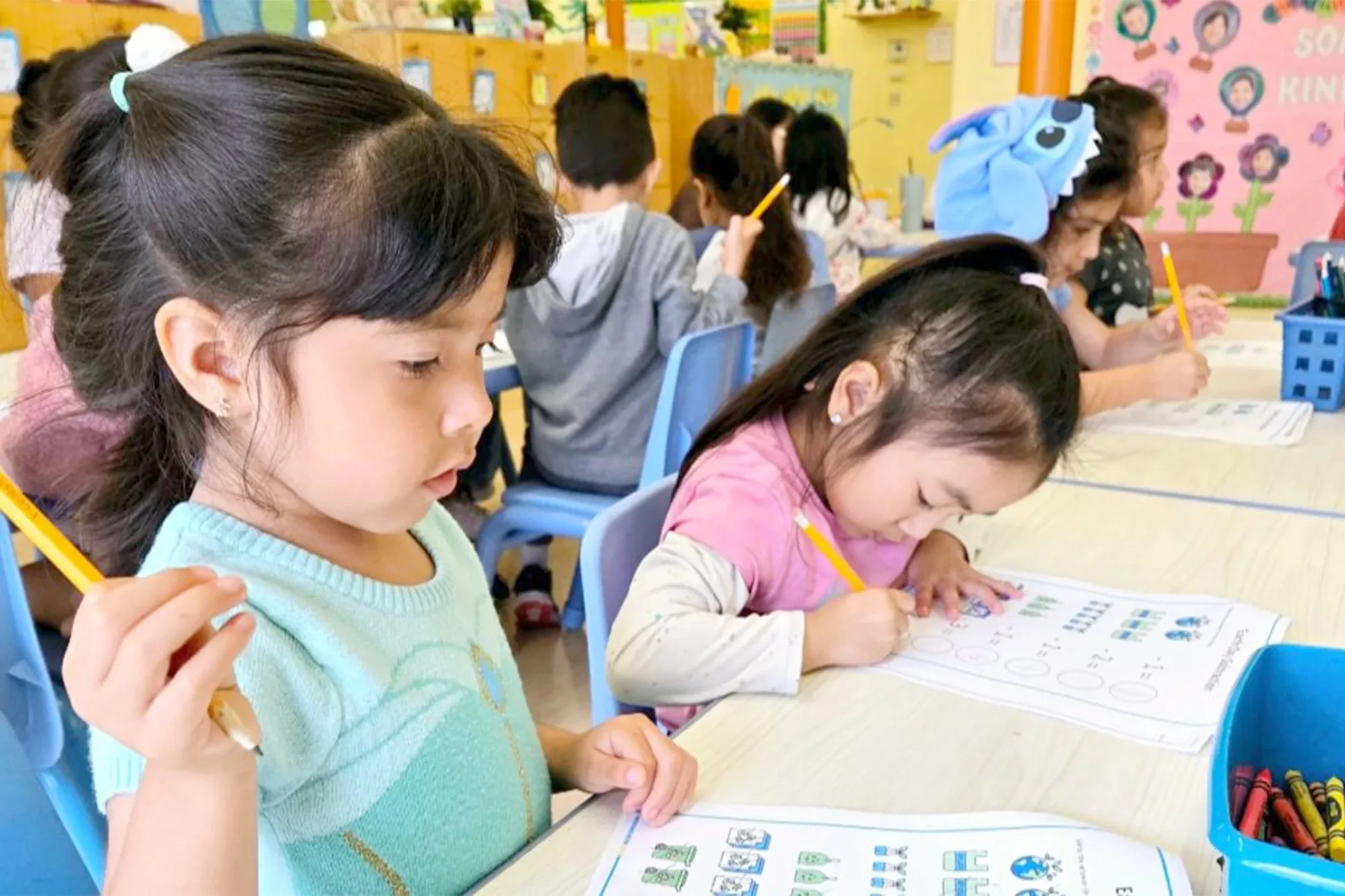 Four to five year old child working on a paper assignment indoors as part of structured Pre-K academic learning at Newport Ave Preschool