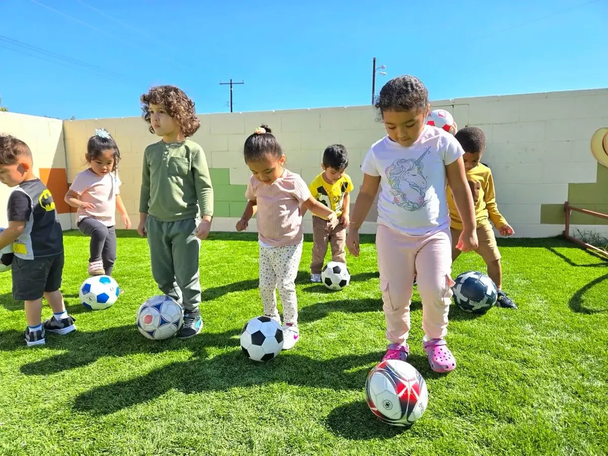 Children playing football outdoors representing the active, enriched programs included in affordable tuition at Newport Ave Preschool