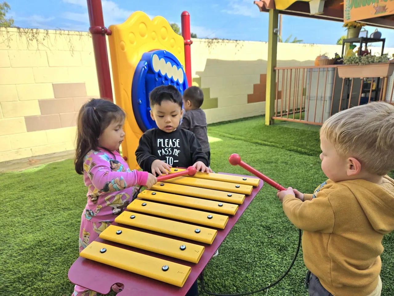 Children expressing creativity and playing musical instruments in the outdoor music garden at Newport Ave Preschool
