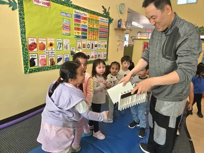Young child practicing Tae Kwon Do with an instructor breaking a board during martial arts enrichment at Newport Ave Preschool