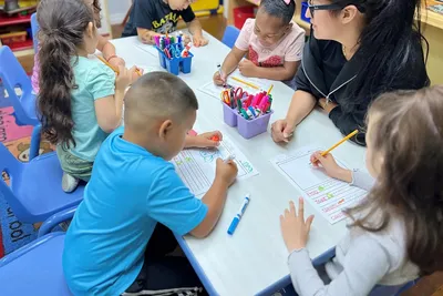 Pre-K children working on paper homework activities supporting parent-teacher partnership and consistent skill reinforcement at Newport Ave Preschool