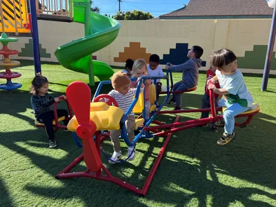 Children playing on a safe outdoor playground with age-appropriate equipment and gross motor activities at Newport Ave Preschool
