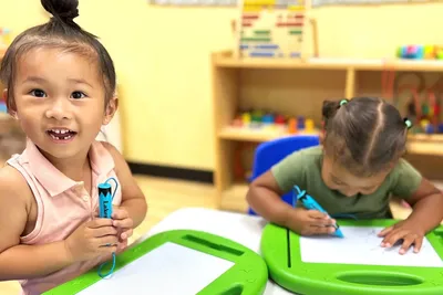 Teacher guiding young children through a hands-on art activity in a preschool classroom at Newport Ave Preschool